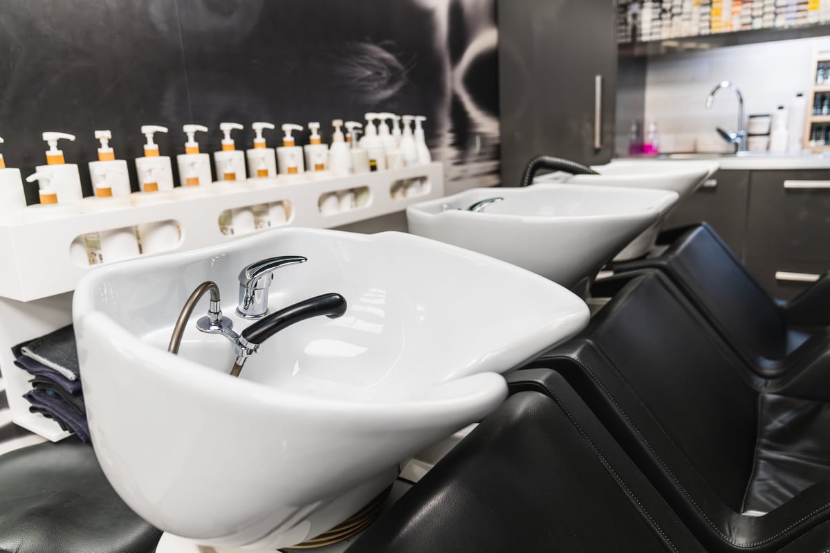 Hair salon interior featuring multiple shampoo sinks and comfortable chairs, ready for hair washing services