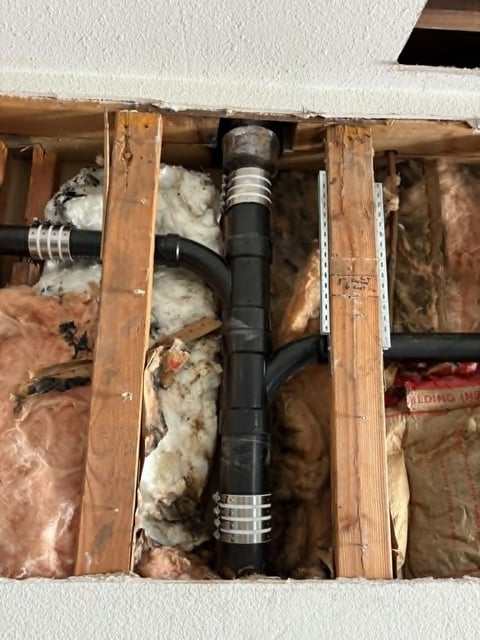 Open wall cavity showing exposed plumbing pipe with insulation and wooden framing studs