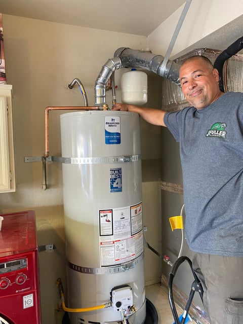 Man pointing to an installed residential water heater in a basement utility room